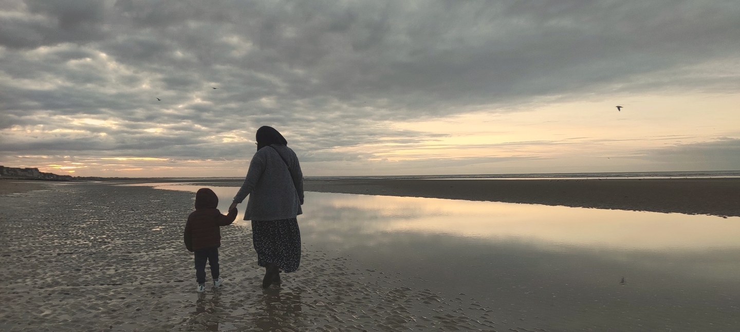 Mère et enfant de dos sur une plage au crépuscule