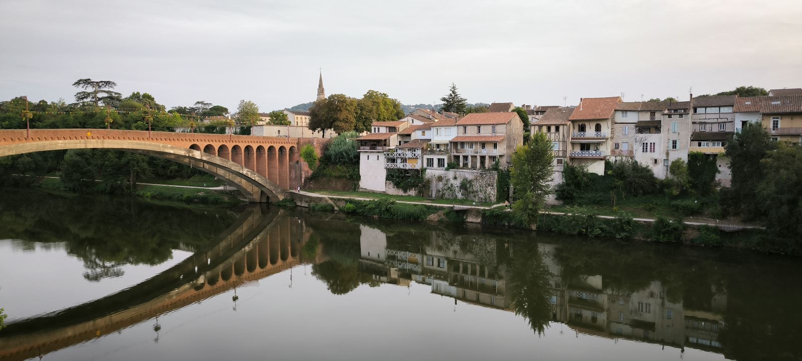 Pont et maisons de village reflétés dans une rivière calme en France