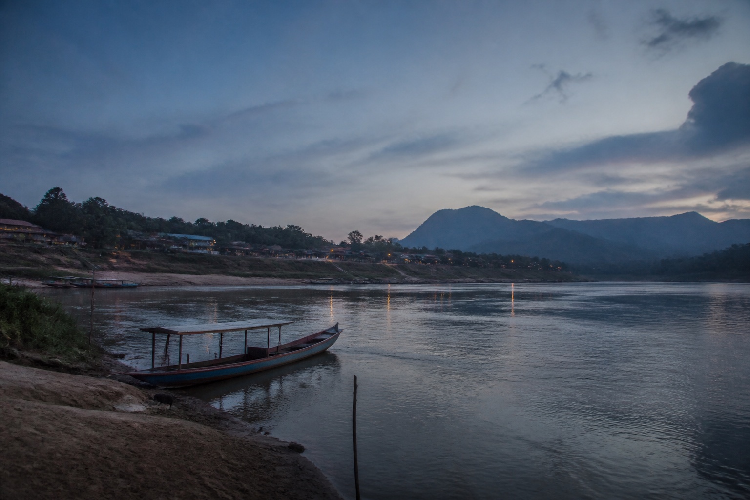 Bateau en bois amarré au bord du Mékong à la tombée du jour