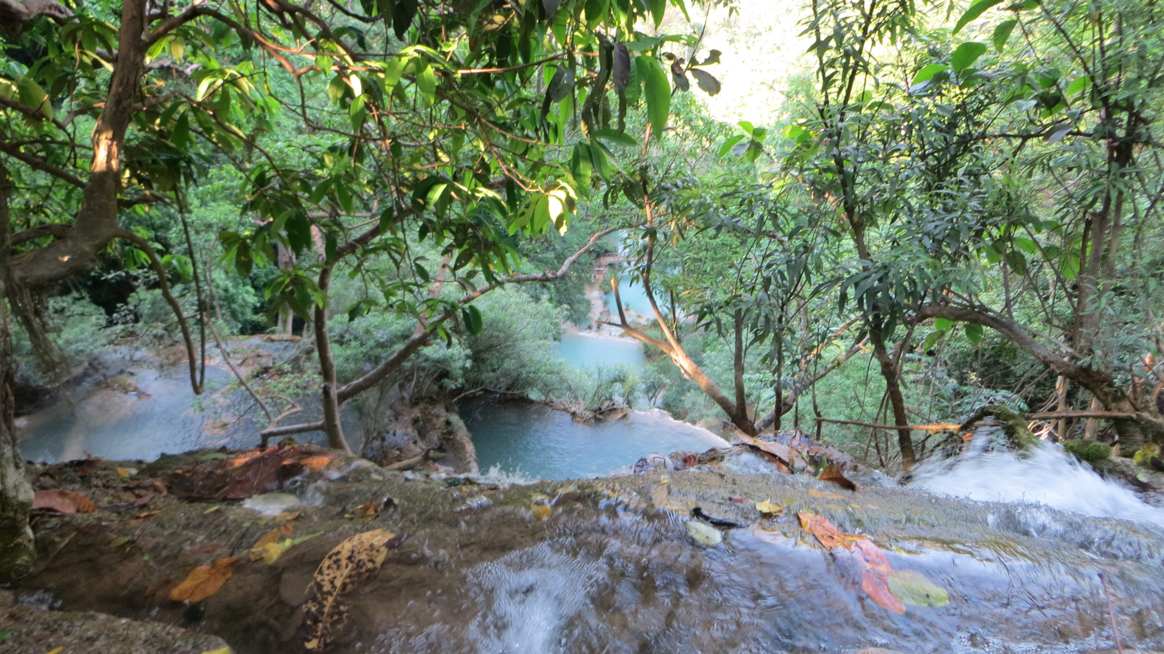 Bassins turquoise et végétation vus depuis le haut d’une cascade au Laos