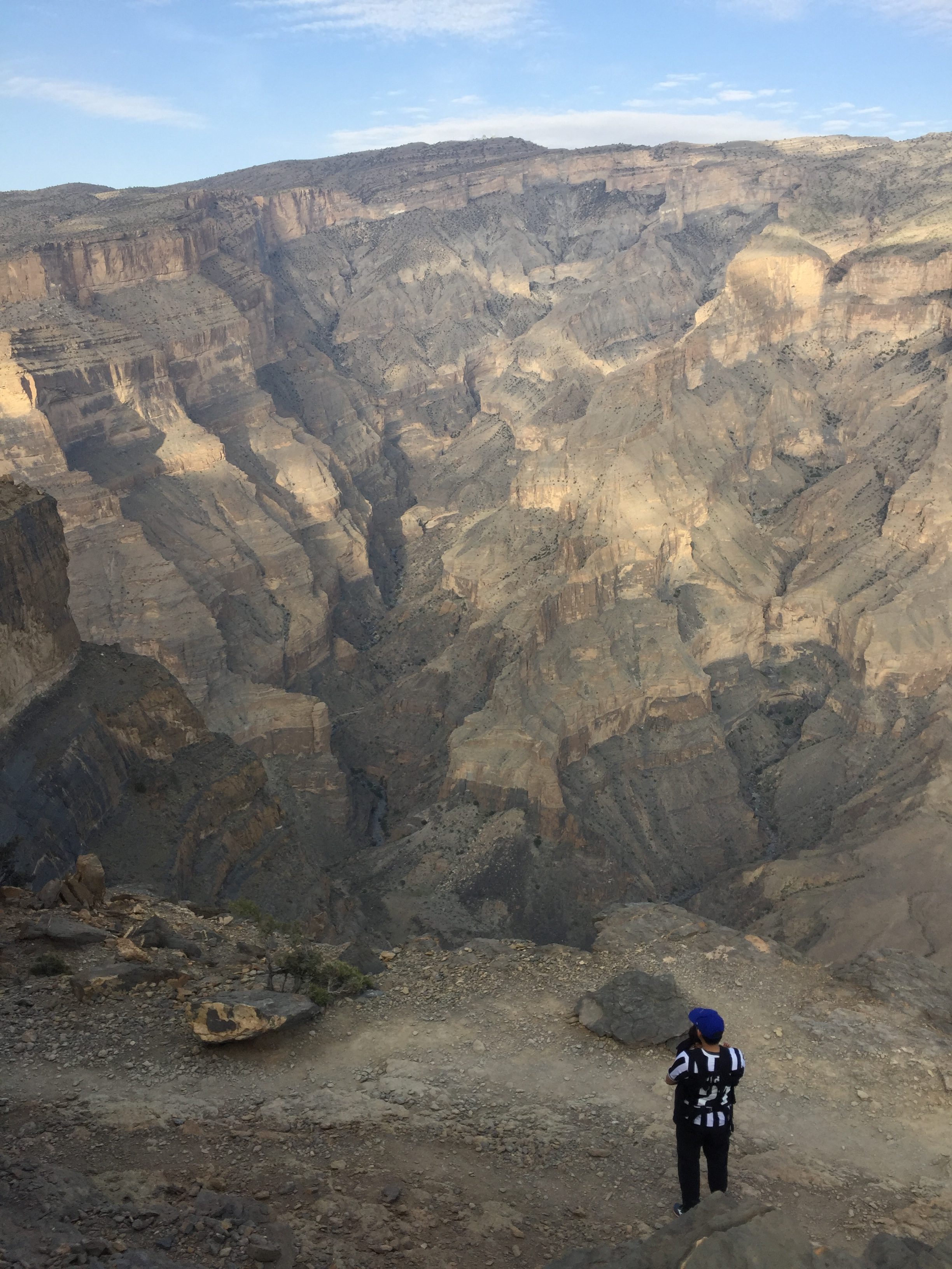 Voyageur vu de dos face à l’immensité d’un canyon omanais