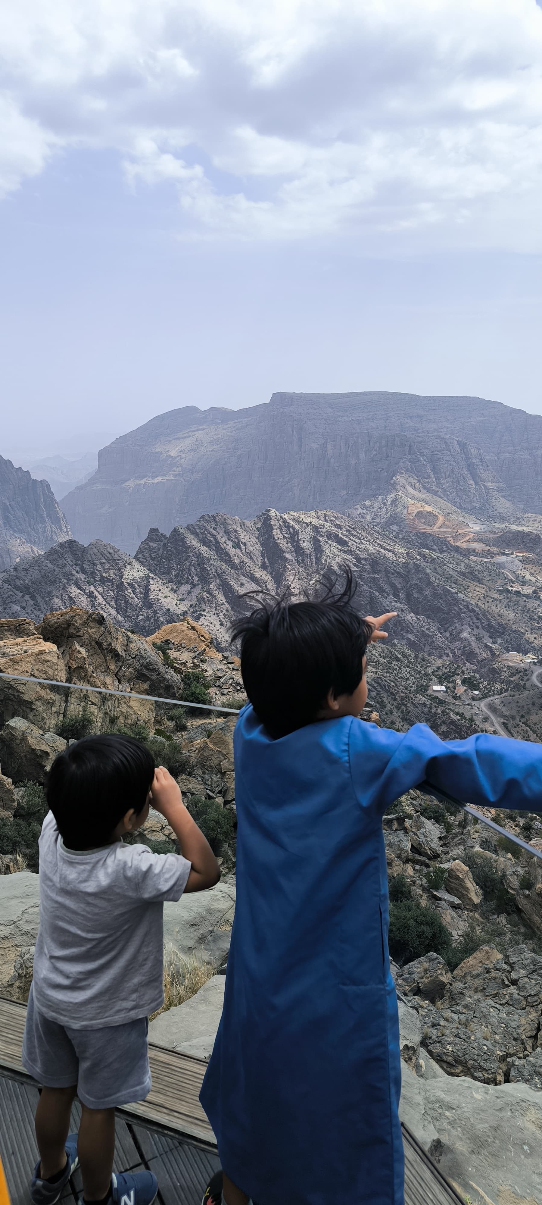 Deux enfants vus de dos observant les reliefs d’un canyon à Oman
