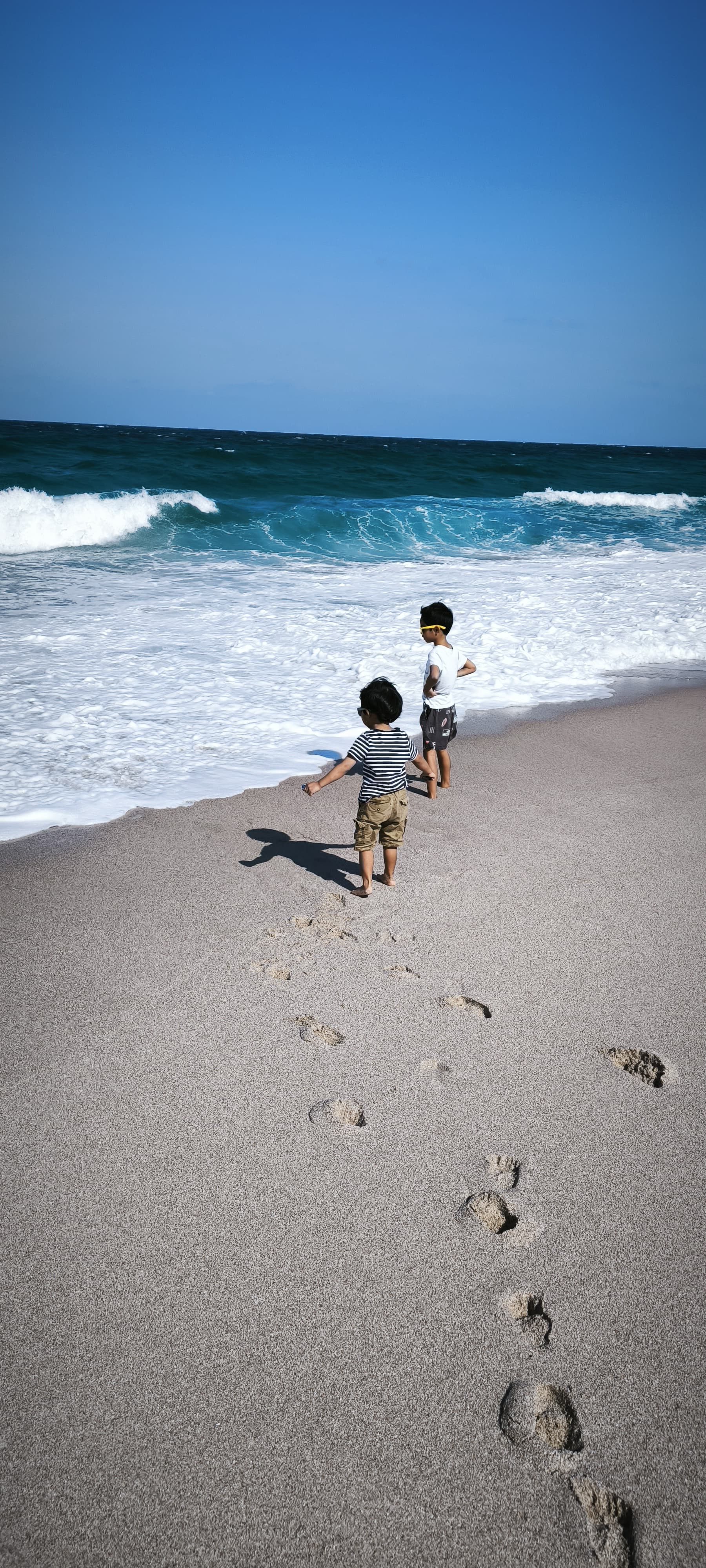 Deux enfants suivant des traces de pas vers l’océan