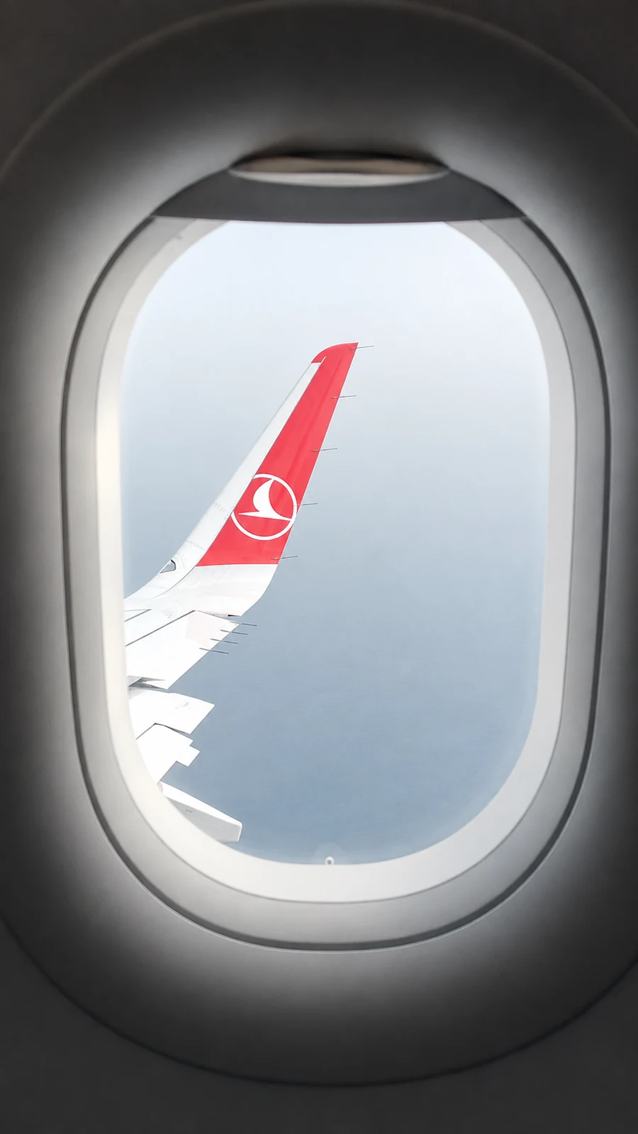 Vue d’une aile d’avion à travers un hublot pendant le voyage.